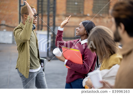 Black girl and guy hold hands near their friends Black girl and guy hold hands near their friends 83996163