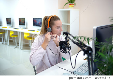 young woman is streaming while sitting in coworking at the computer young woman is streaming while sitting in coworking at the computer 83996183