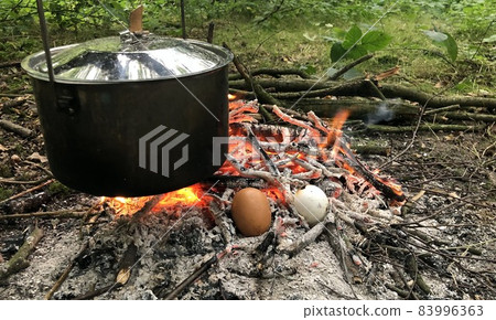 cooking on an open fire during bushcraft in the woods cooking on an open fire during bushcraft in the woods 83996363