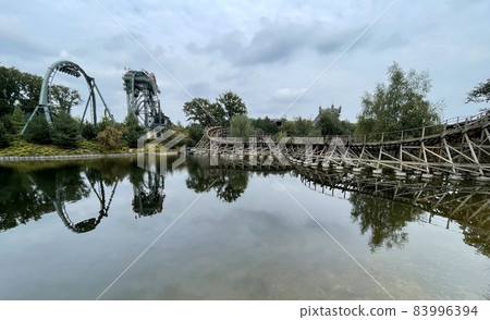 two rollercoasters next to a lake in a themepark 83996394