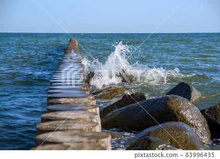 Waves crashing on breakwaters. Sea wave splashing. Waves and a storm at sea. Baltic Sea. 83996435