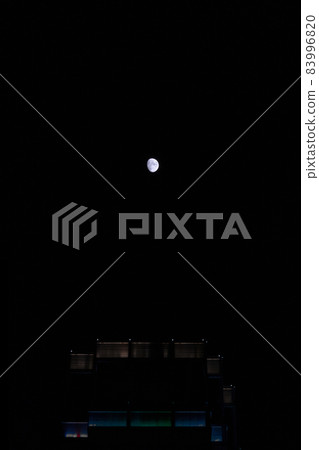 moon floating in the city night sky 83996820
