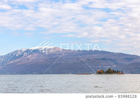 Small Rabbit island in Lake Garda against the background of the Alps (Autumn period) 83998128