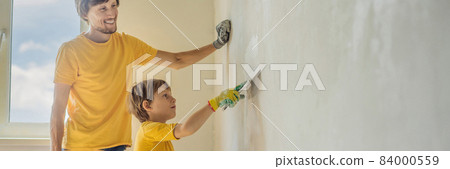 Man with his son makes repairs at home, he teaches children to plaster the walls with a spatula in his hands BANNER, LONG FORMAT 84000559