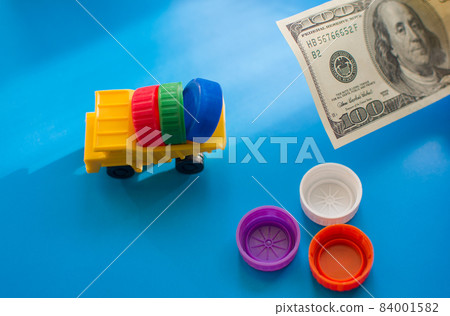 Dump truck with colored plastic bottle caps on blue background. Dump truck with colored plastic bottle caps on blue background. 84001582