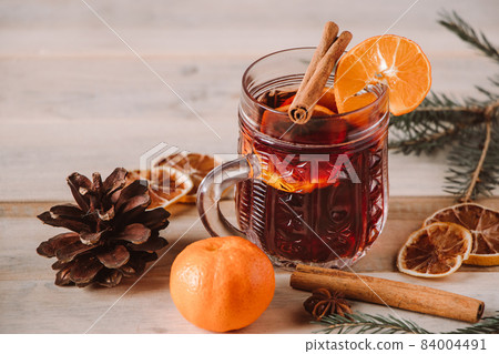 Hot mulled wine with fruits and spices on a wooden background. Winter warming drink for the holidays. 84004491