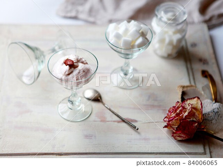 Pink dessert in a vintage glass, sugar cubes and old rose flower on a wooden table. Ice Cream cup for Dessert Cake Juice. Shabby chic style decorations. European Vintage Embossed Bowl Creative Glass Pink dessert in a vintage glass, sugar cubes and old rose flower on a wooden table. Ice Cream cup for Dessert Cake Juice. Shabby chic style decorations. European Vintage Embossed Bowl Creative Glass 84006065