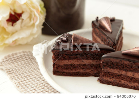 Chocolate cake slice with curl on white background. cake with whipped cream and mascarpone filling. Delicious naked cake filled with cream, topped with melted chocolate and decorated with flowers, 84006070