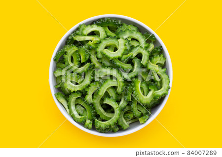 Sliced bitter gourd in white bowl on yellow background. 84007289