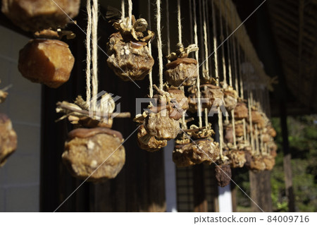 Dried persimmon (Dried persimmon hung on the eaves of an old Japanese farmhouse. Nostalgic scenery.) Location: Tokyo Dried persimmon (Dried persimmon hung on the eaves of an old Japanese farmhouse. Nostalgic scenery.) Location: Tokyo 84009716