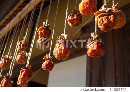 Dried persimmon (Dried persimmon hung on the eaves of an old Japanese farmhouse. Nostalgic scenery.) Location: Tokyo Dried persimmon (Dried persimmon hung on the eaves of an old Japanese farmhouse. Nostalgic scenery.) Location: Tokyo 84009721
