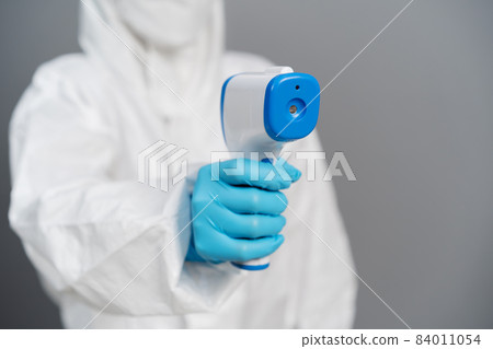 doctor in protective PPE suit scanning with infrared thermometer 84011054