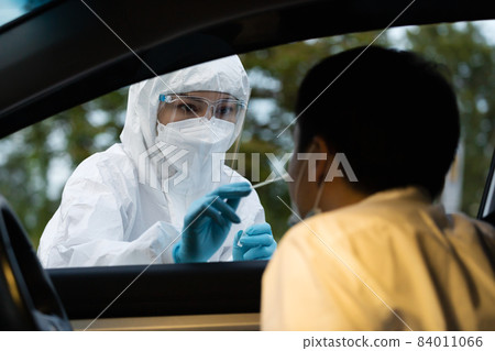 doctor in PPE suit test coronavirus(covid-19) to man in car by nasal swab cotton, drive thru test doctor in PPE suit test coronavirus(covid-19) to man in car by nasal swab cotton, drive thru test 84011066