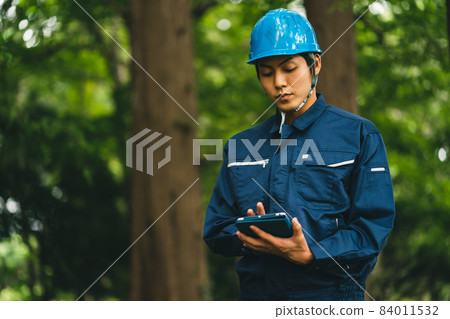 Park maintenance contractor wearing a helmet Park maintenance contractor wearing a helmet 84011532
