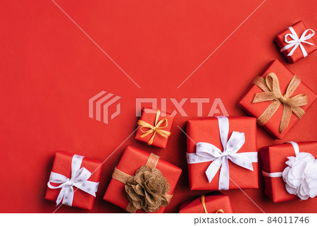 Gift boxes with white and brown bows on a red backdrop. 84011746