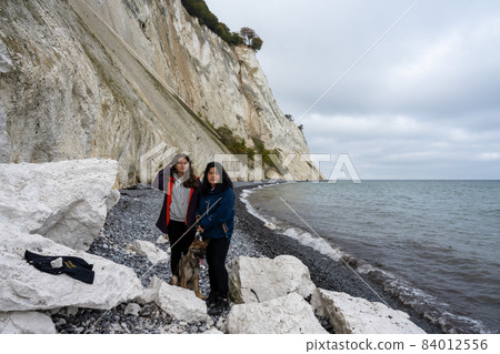 A mother and daughter with a dog in front of a beautiful chalk cliff 84012556