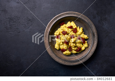 Traditional Italian potato gnocchi with parmesan and dried tomatoes in rustic plate on graphite Traditional Italian potato gnocchi with parmesan and dried tomatoes in rustic plate on graphite 84012681