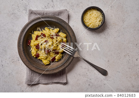Traditional Mediterranean and Alpine potato gnocchi with parmesan and dried tomatoes in ceramic 84012683