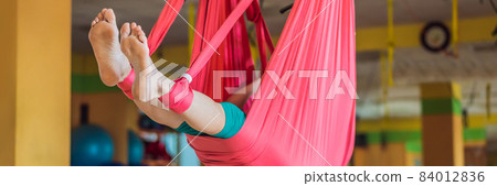 Senior mature woman practices anti-gravity yoga with a hammock in a studio. Lifestyle BANNER, LONG FORMAT Senior mature woman practices anti-gravity yoga with a hammock in a studio. Lifestyle BANNER, LONG FORMAT 84012836