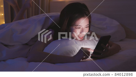 woman use smartphone on bed 84012898