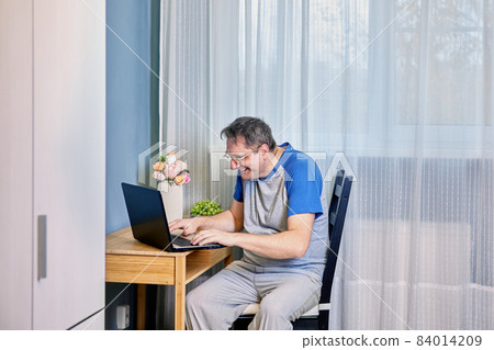 Mature man with laptop works from home that is remotely or teleworking. Mature man with laptop works from home that is remotely or teleworking. 84014209