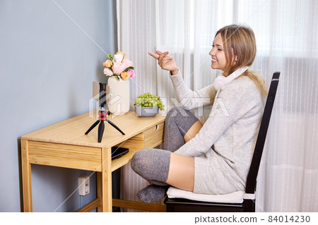 Streaming for social networks from female vlogger who secured smartphone in holder on tripod. Streaming for social networks from female vlogger who secured smartphone in holder on tripod. 84014230
