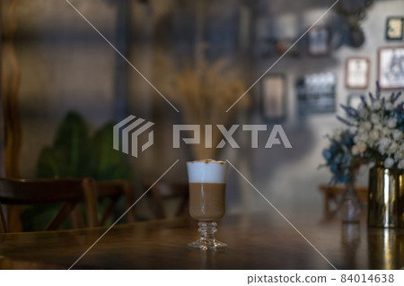 Glass cup with latte is on the table in coffee shop. Glass with caramel cappuccino on the table in the restaurant. Photo for the menu, advertising Glass cup with latte is on the table in coffee shop. Glass with caramel cappuccino on the table in the restaurant. Photo for the menu, advertising 84014638