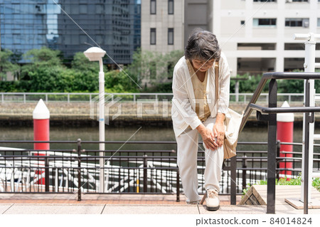 Knee pain senior female outdoor stairs 84014824