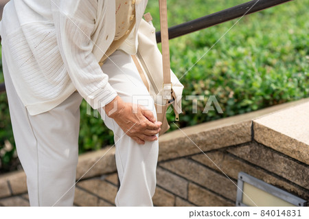 Knee pain senior female outdoor stairs 84014831