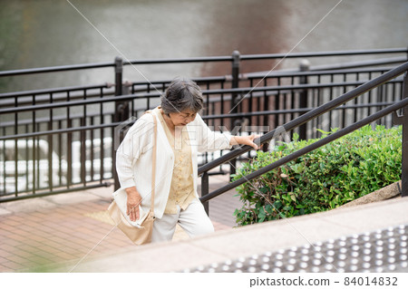 Knee pain senior female outdoor stairs 84014832