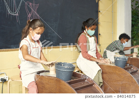 Row of pupils sitting along blackboard and sculpting clay pots Row of pupils sitting along blackboard and sculpting clay pots 84014875