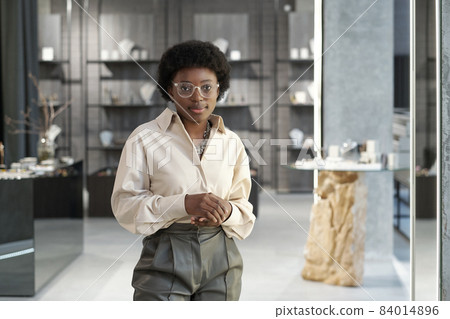 Young African clerk or owner of jewelry store standing against displays 84014896
