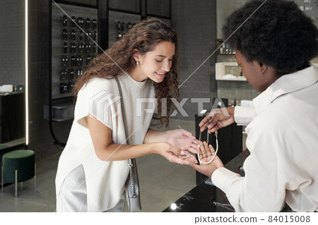 Young African shop asistant helping one of customers Young African shop asistant helping one of customers 84015008