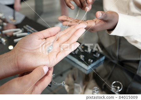 Hands of young woman holding silver chain with pendant Hands of young woman holding silver chain with pendant 84015009