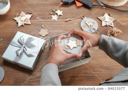 Hands of girl holding handmade xmas toy over box 84015077