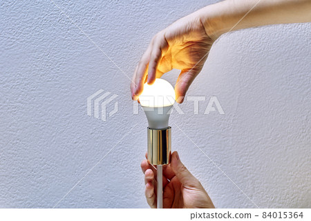 Replacing Electric Light Bulb in Ceiling Lighting Fixture, repairman changes lamp in chandelier. Replacing Electric Light Bulb in Ceiling Lighting Fixture, repairman changes lamp in chandelier. 84015364