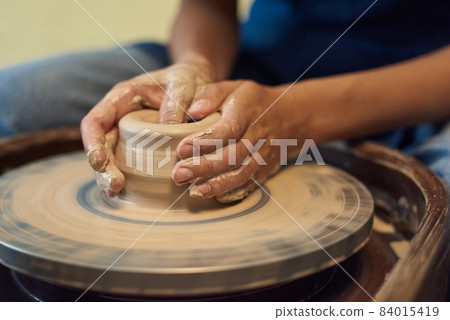 Hands of young craftsperson holding by rotating pottery wheel Hands of young craftsperson holding by rotating pottery wheel 84015419