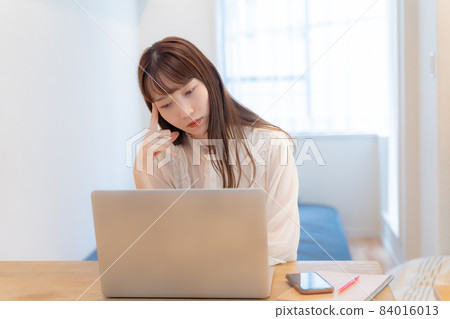A woman troubled watching a personal computer A woman troubled watching a personal computer 84016013