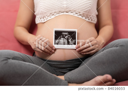 Close up Happy Pregnant Woman holding ultrasound image stroking big belly with love isolated on couch,Pregnancy of young woman enjoy with future life,Motherhood and Pregnant Concept Close up Happy Pregnant Woman holding ultrasound image stroking big belly with love isolated on couch,Pregnancy of young woman enjoy with future life,Motherhood and Pregnant Concept 84016033