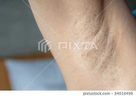Close up of woman showing her unshaved armpit. Unshaven women often meet other criteria for traditional feminine beauty. Close up of woman showing her unshaved armpit. Unshaven women often meet other criteria for traditional feminine beauty. 84018499