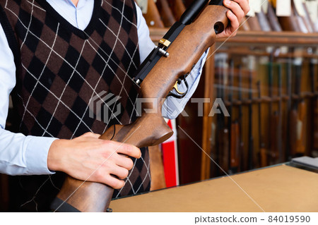 Air rifle in the hands of the owner of gun shop 84019590