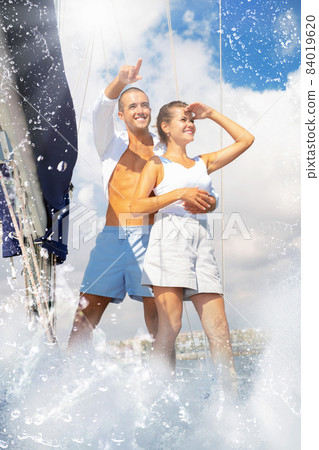 Loving couple standing on deck of sailboat during sea trip along 84019620