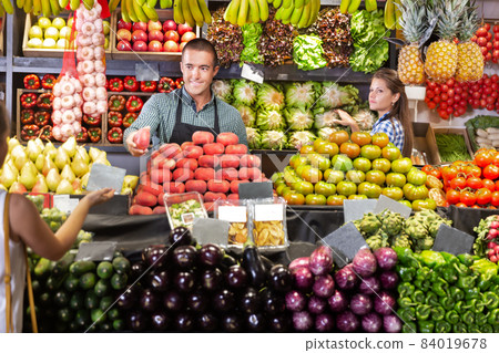 Shop assistants selling fruits and vegetables to buyer Shop assistants selling fruits and vegetables to buyer 84019678