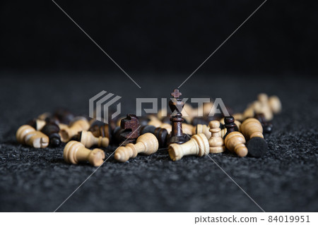 Scattered chess pieces on a blurred black background. Scattered chess pieces on a blurred black background. 84019951