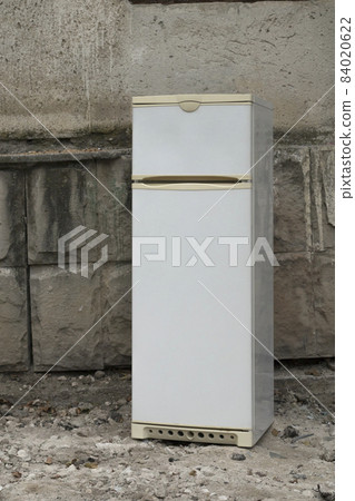 An old refrigerator was thrown away on the street. 84020622