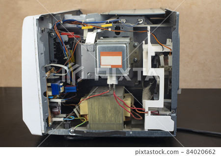 Repair of a microwave oven, repair of household appliances. Microwave with side panel removed, internal device visible Repair of a microwave oven, repair of household appliances. Microwave with side panel removed, internal device visible 84020662