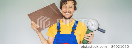 A tiler, a tiling specialist, holds a tile cutter in his hands BANNER, LONG FORMAT A tiler, a tiling specialist, holds a tile cutter in his hands BANNER, LONG FORMAT 84021020
