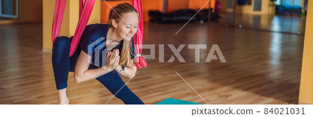 Young beautiful woman practicing aerial yoga in gym. Lifestyle BANNER, LONG FORMAT Young beautiful woman practicing aerial yoga in gym. Lifestyle BANNER, LONG FORMAT 84021031