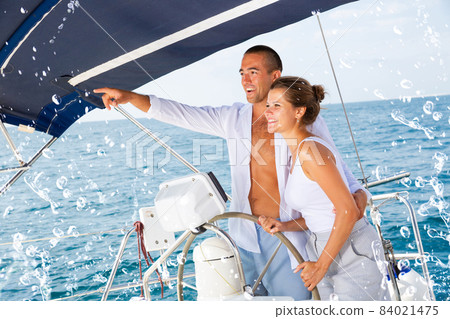 Man on yacht wheel pointing to horizon Man on yacht wheel pointing to horizon 84021475