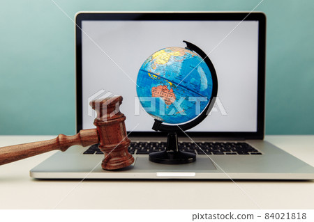 Wooden judge gavel and globe on laptop. International law concept Wooden judge gavel and globe on laptop. International law concept 84021818
